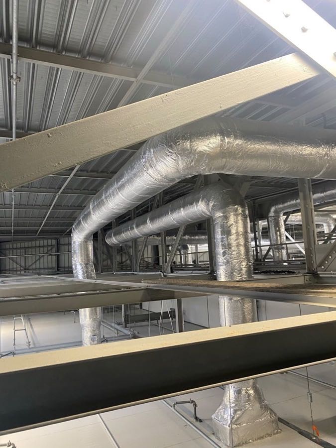 Réseau de gaines circulaires calorifugées dans un bâtiment industriel